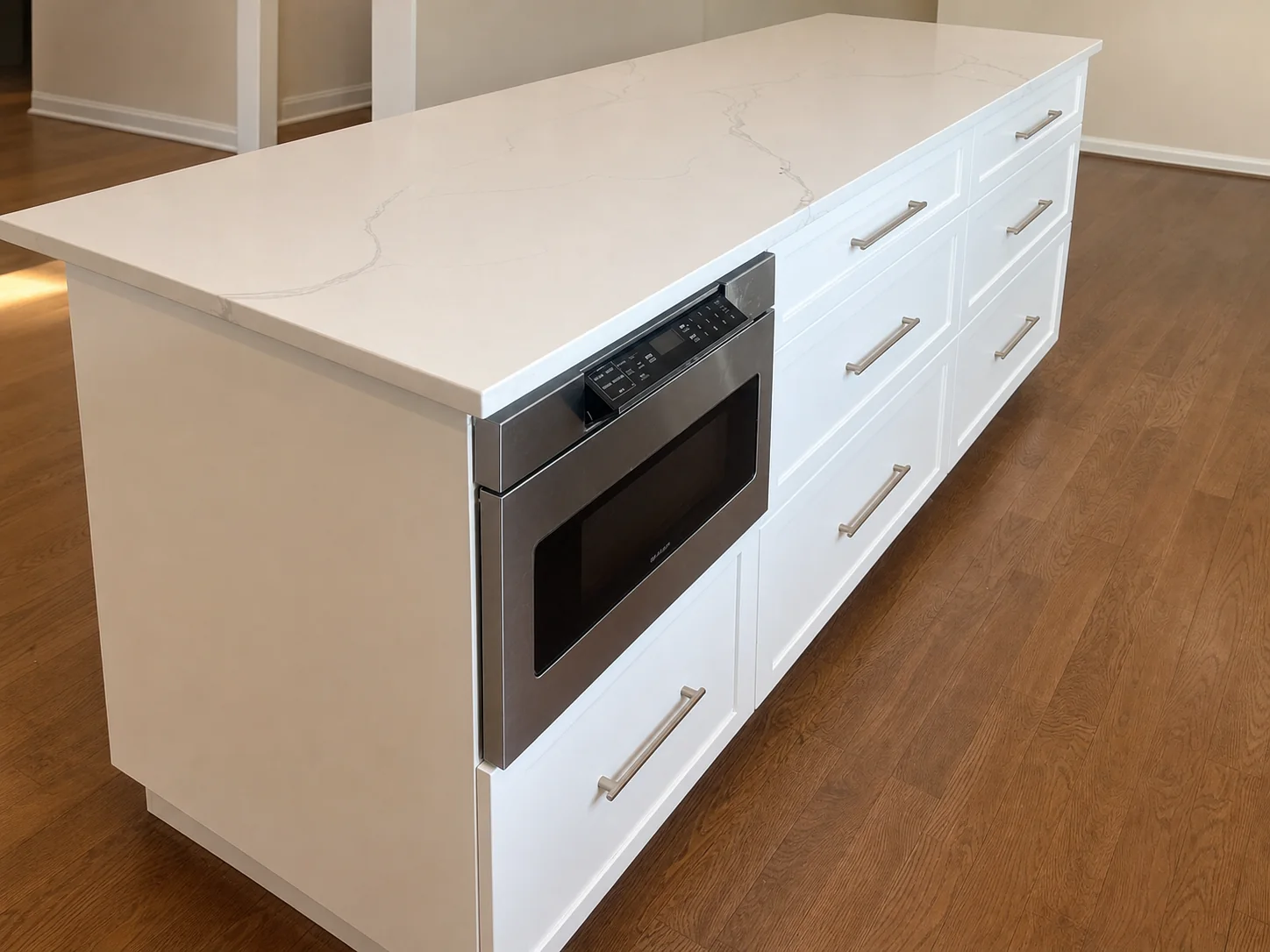 White custom kitchen island with integrated appliance and storage built by HUFCO