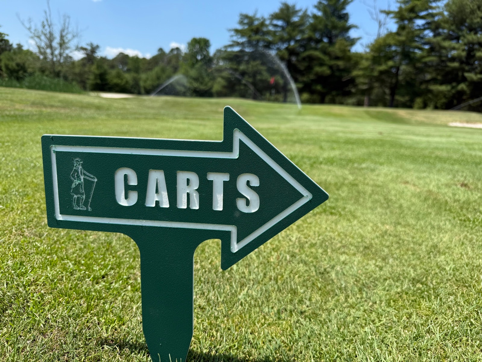 Green golf cart direction sign installed on a golf course